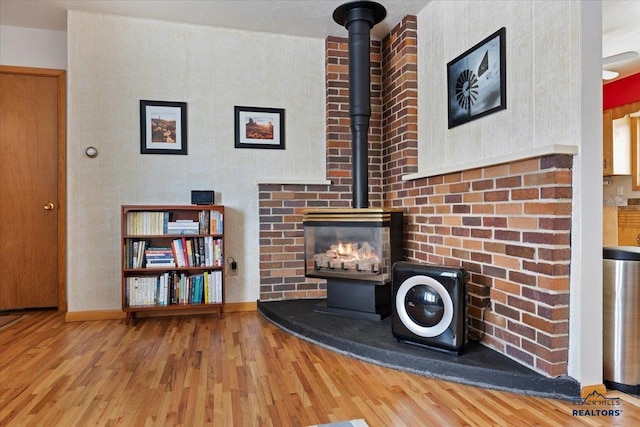 room details featuring a wood stove, wood finished floors, and baseboards