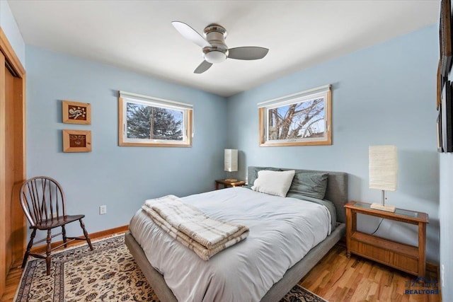 bedroom featuring baseboards, a closet, light wood finished floors, and ceiling fan