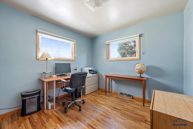 office area with light wood finished floors, visible vents, and baseboards