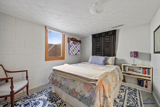 bedroom featuring concrete block wall and a textured ceiling