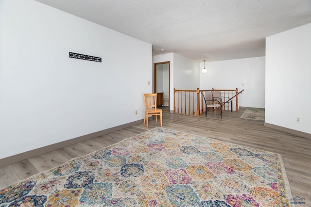 living area featuring an upstairs landing, a textured ceiling, and wood finished floors