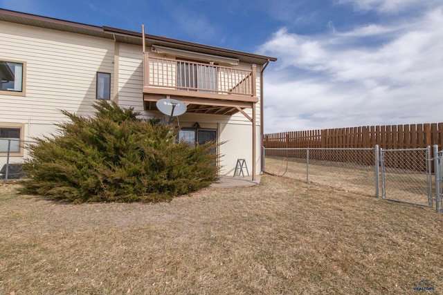 back of house with fence, a balcony, and a gate