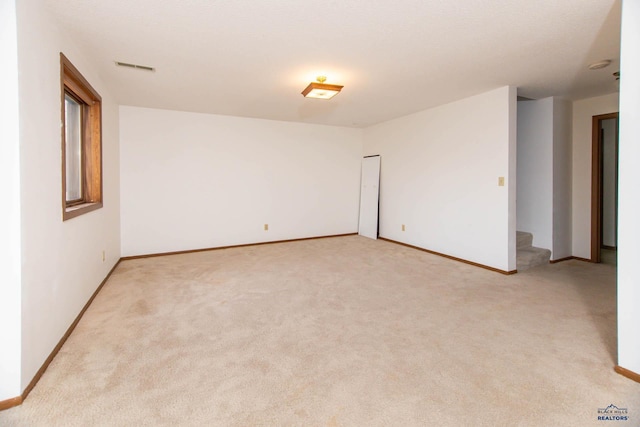 spare room with light carpet, visible vents, stairs, and baseboards