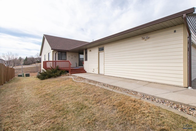 view of front of home featuring fence, roof with shingles, a front yard, a deck, and a garage