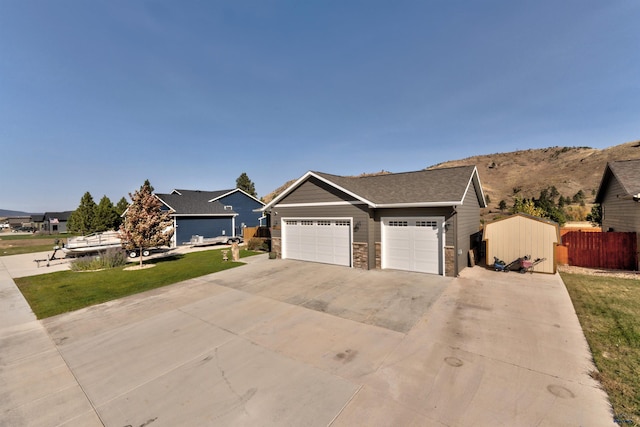 view of front of house featuring fence, concrete driveway, a front yard, stone siding, and an attached garage