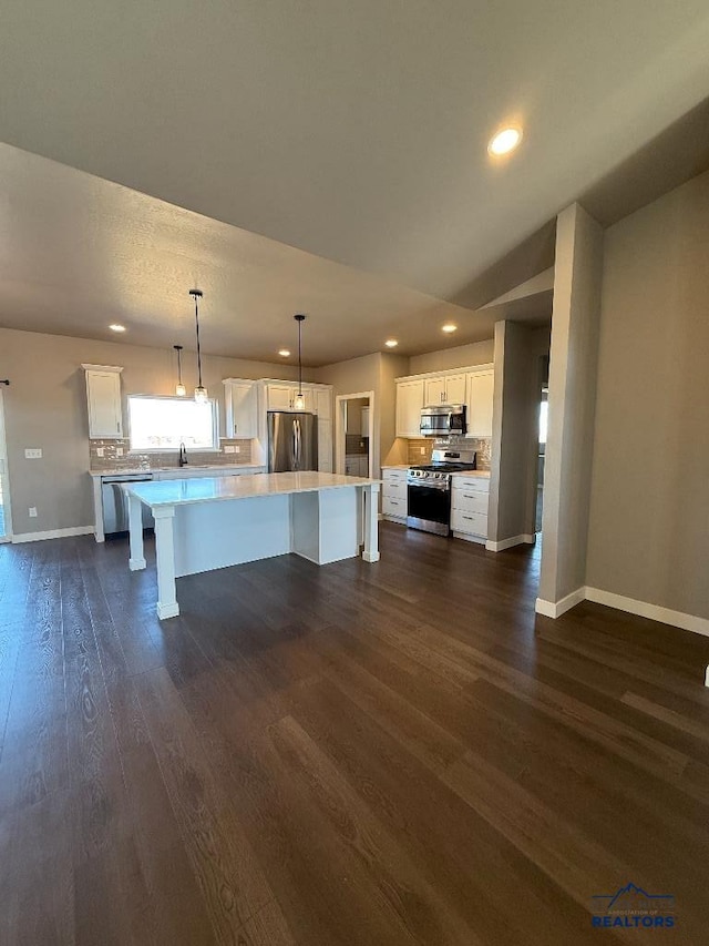 kitchen with stainless steel appliances, white cabinetry, dark wood-type flooring, and light countertops