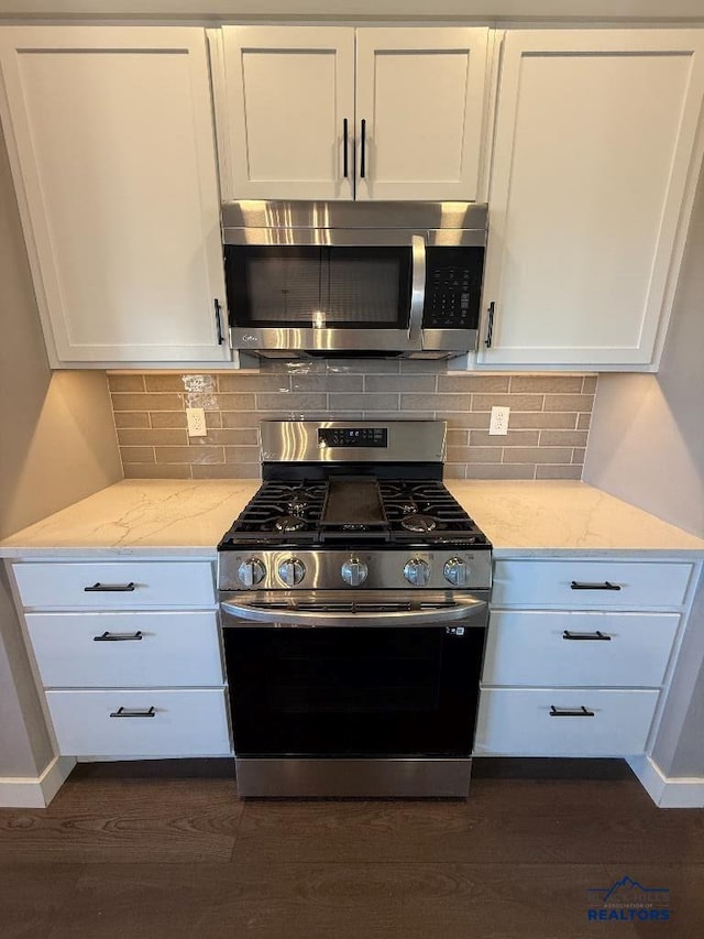 kitchen with light stone counters, tasteful backsplash, dark wood-style floors, stainless steel appliances, and white cabinets