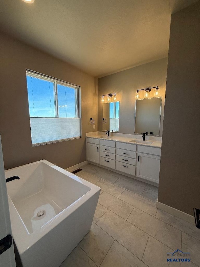 bathroom with double vanity, a sink, baseboards, and a freestanding tub