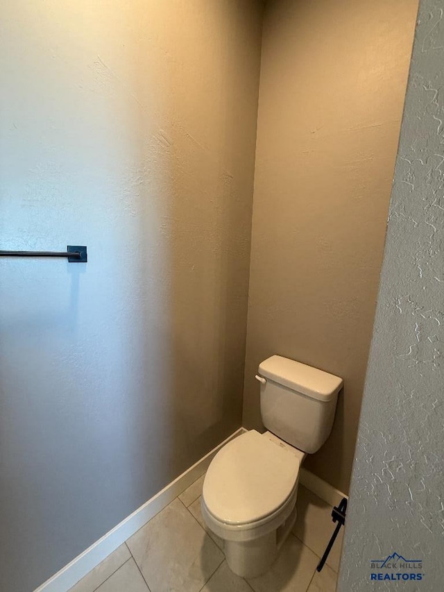 bathroom featuring tile patterned floors, baseboards, and toilet