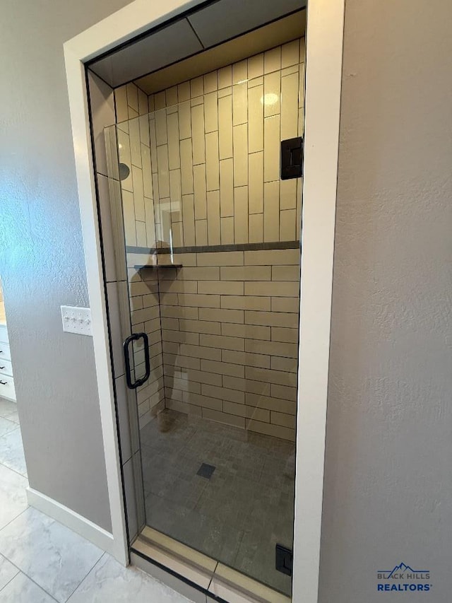 bathroom featuring a shower stall, marble finish floor, and baseboards