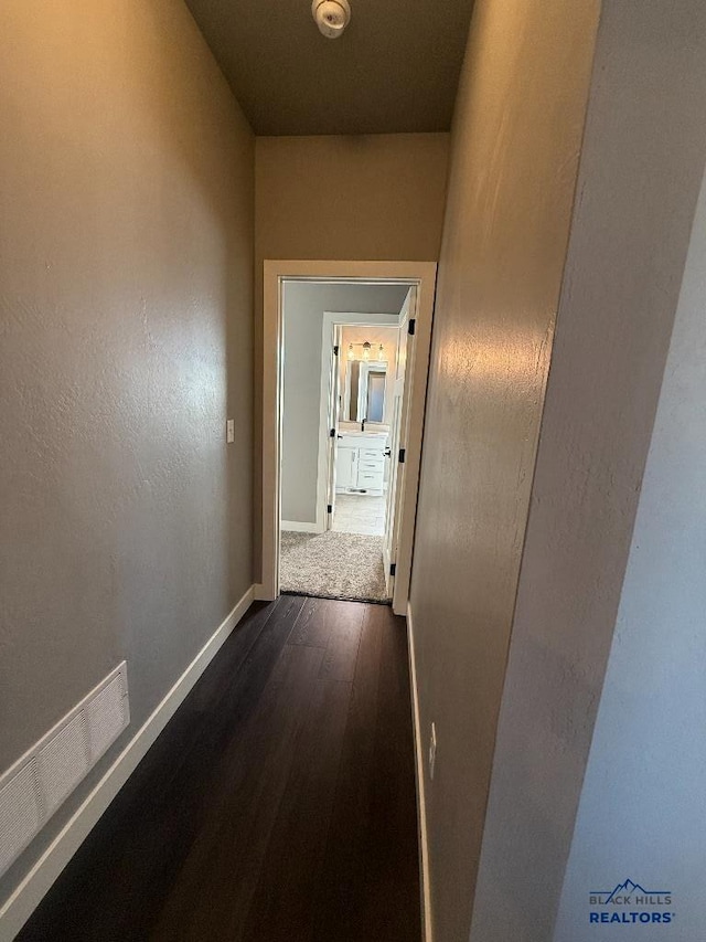 hallway featuring baseboards and dark wood-style flooring