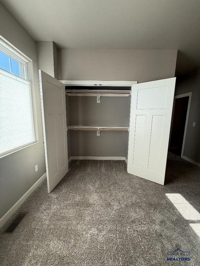 unfurnished bedroom featuring visible vents, baseboards, carpet, and a closet