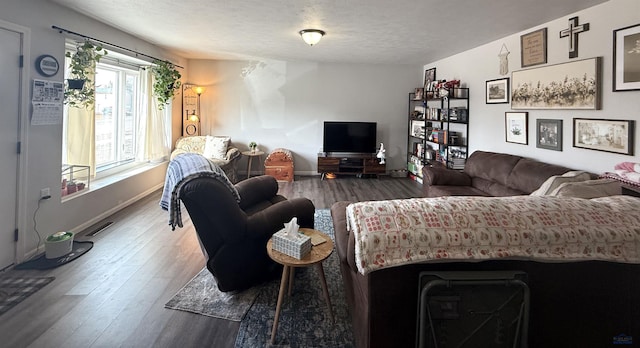 living room with visible vents, wood finished floors, baseboards, and a textured ceiling