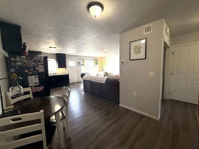 interior space with dark wood-type flooring, baseboards, visible vents, and a textured ceiling