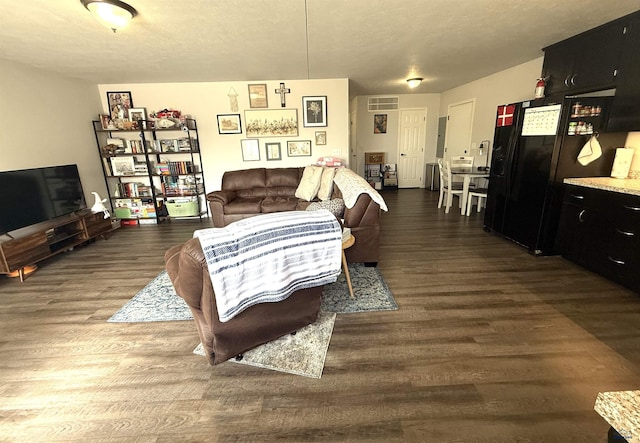 living area featuring visible vents, a textured ceiling, and dark wood-type flooring