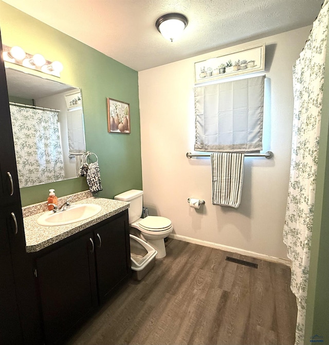 full bathroom with visible vents, baseboards, toilet, wood finished floors, and vanity