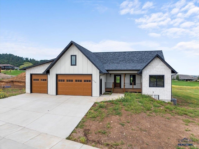 modern farmhouse featuring board and batten siding, a shingled roof, a porch, concrete driveway, and an attached garage