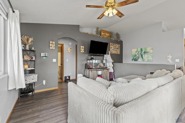 living area featuring lofted ceiling, a ceiling fan, arched walkways, baseboards, and dark wood-style flooring