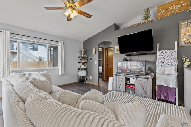 living area with baseboards, vaulted ceiling, wood finished floors, arched walkways, and a ceiling fan