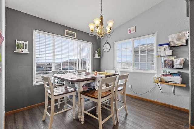 dining area featuring a chandelier, lofted ceiling, baseboards, and wood finished floors