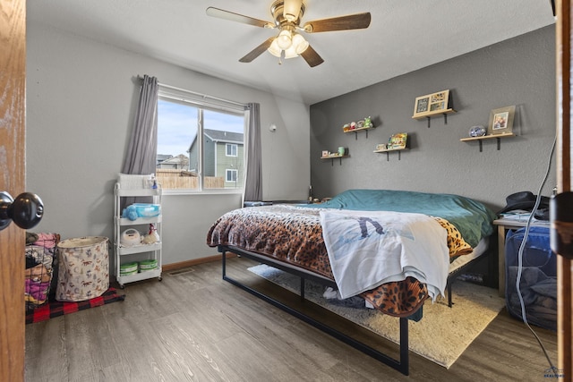 bedroom featuring wood finished floors, baseboards, and ceiling fan