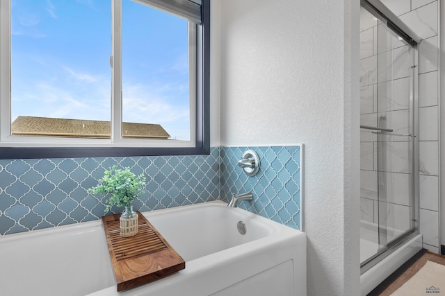 bathroom featuring a shower stall, a bath, and a textured wall