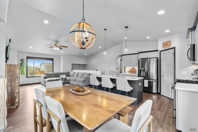 dining area featuring recessed lighting, ceiling fan with notable chandelier, dark wood-style flooring, and vaulted ceiling