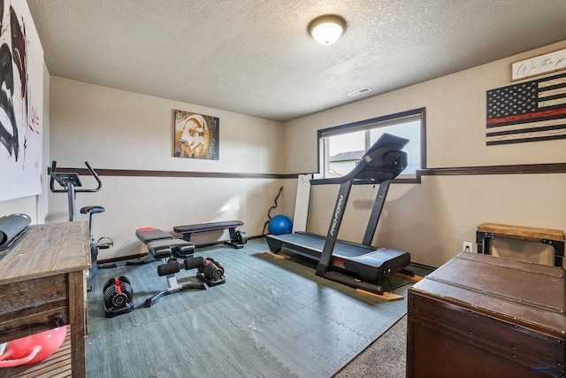 workout room featuring visible vents, baseboards, and a textured ceiling