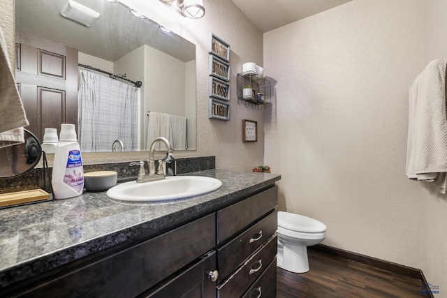 bathroom with vanity, a shower with curtain, wood finished floors, toilet, and a textured wall