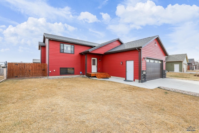 view of front facade with a front lawn, fence, concrete driveway, an attached garage, and a gate