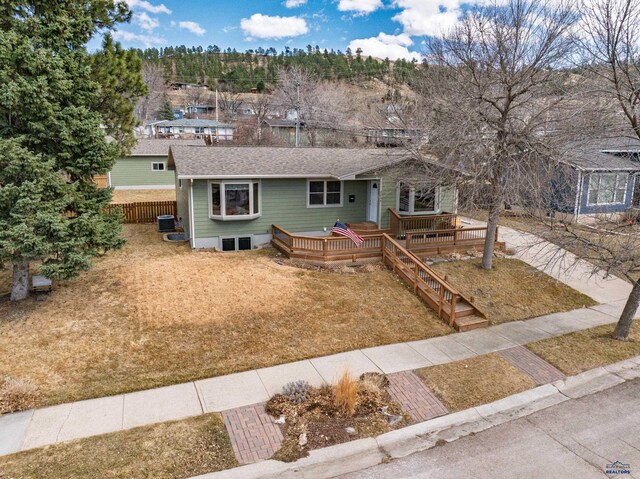 2204 Cruz Dr, Rapid City, SD 57702 - view of front of house with a shingled roof, fence, a wooden deck, a front yard, and central AC unit