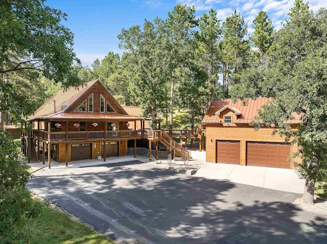 view of front facade featuring driveway, a standing seam roof, stairs, a garage, and metal roof