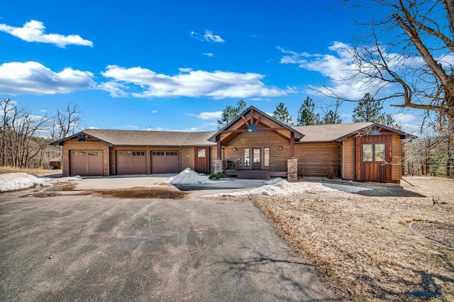 view of front of home with aphalt driveway, a garage, and roof with shingles