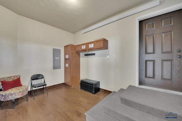 interior space with electric panel, baseboards, and light wood-style floors