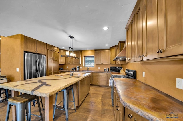 kitchen with wall chimney exhaust hood, brown cabinetry, dark wood-style flooring, and stainless steel appliances