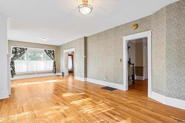 1120 W Blvd, Rapid City, SD 57701 - unfurnished room with baseboards, light wood-style floors, stairs, and wallpapered walls