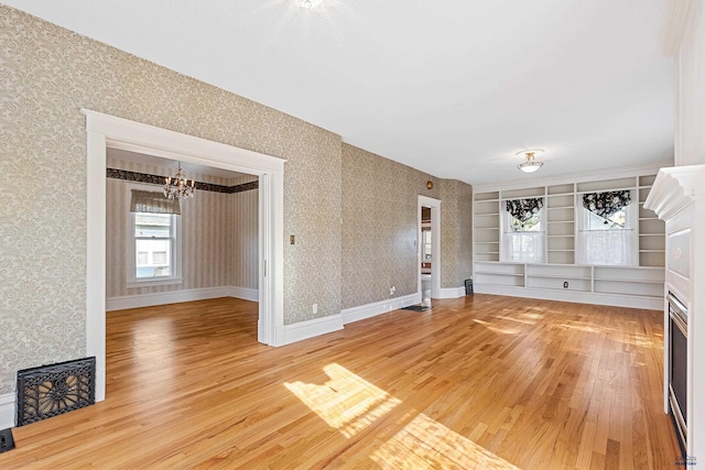 1120 W Blvd, Rapid City, SD 57701 - unfurnished living room featuring wallpapered walls, light wood-style flooring, a notable chandelier, and baseboards