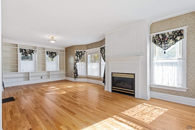 1120 W Blvd, Rapid City, SD 57701 - unfurnished living room featuring light wood finished floors, visible vents, a large fireplace, and wallpapered walls