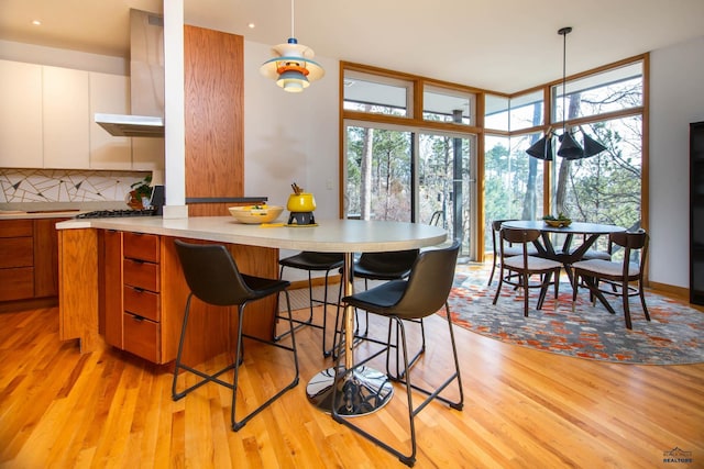 1515 Forest Dr, Rapid City, SD 57701 - kitchen featuring a breakfast bar, tasteful backsplash, floor to ceiling windows, light wood-style floors, and light countertops