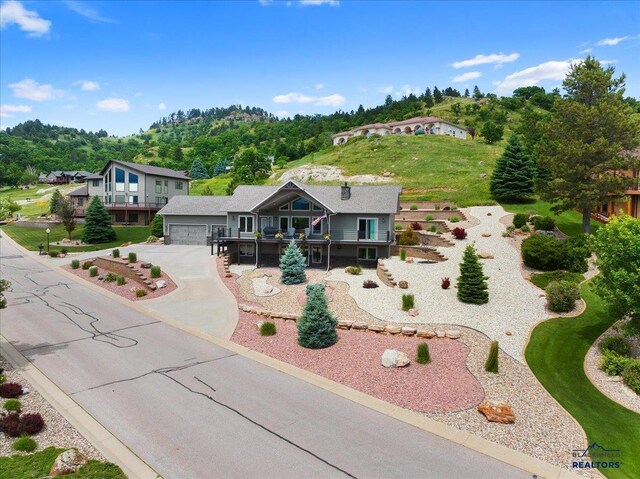 view of front of home with a deck, a patio, stairway, concrete driveway, and a garage