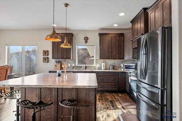 kitchen featuring a sink, dark brown cabinets, backsplash, and stainless steel appliances