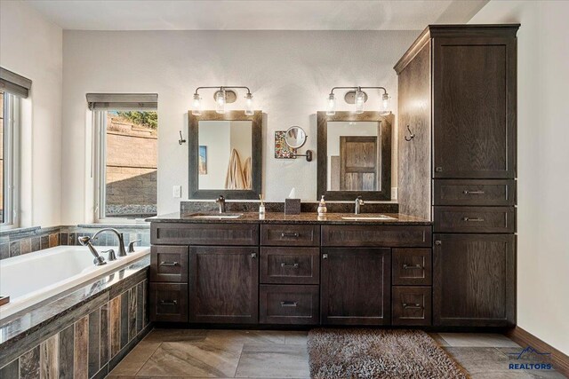 bathroom with double vanity, a bathtub, and a sink