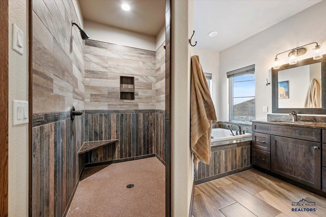 bathroom featuring tiled shower, a garden tub, and vanity
