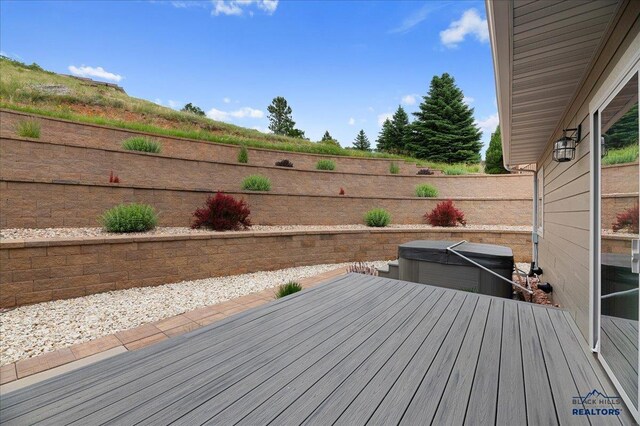 deck featuring a hot tub and a fenced backyard
