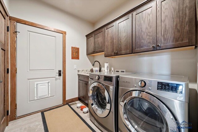 washroom with washing machine and dryer, cabinet space, baseboards, and a sink