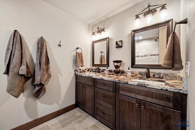 bathroom with double vanity, baseboards, and a sink