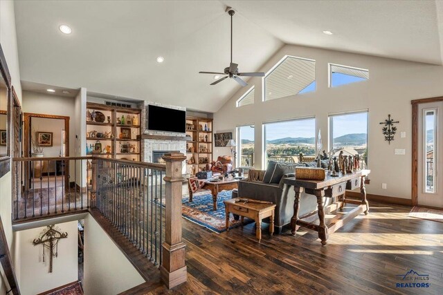 living room featuring a stone fireplace, high vaulted ceiling, ceiling fan, and hardwood / wood-style floors