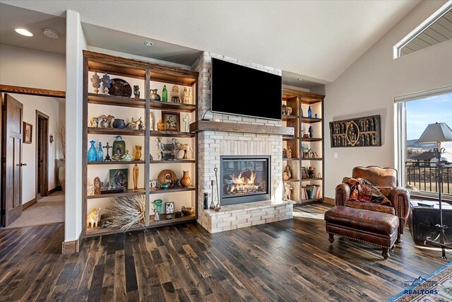 living room with built in features, wood finished floors, baseboards, lofted ceiling, and a fireplace