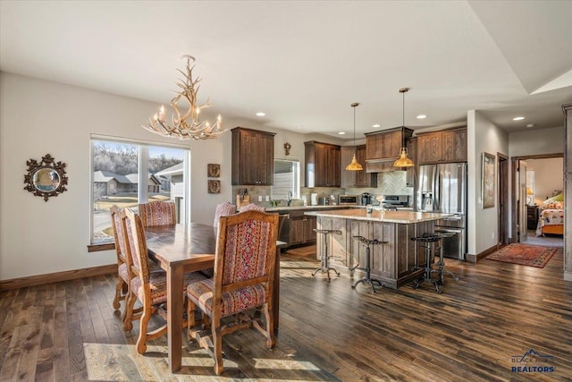 dining area with recessed lighting, baseboards, an inviting chandelier, and dark wood-style floors