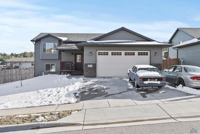 view of front facade featuring driveway, a shingled roof, an attached garage, and fence